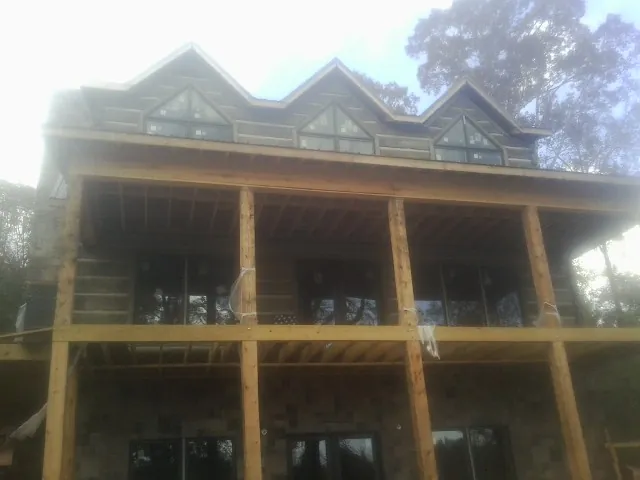 Dormers and porch framing on a large log home under construction — Roof Coating work by our crew in Dexter